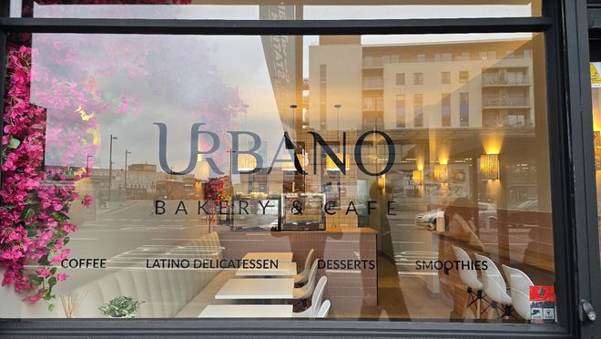 The café window with bougainvillea visible through the glass, cropped above the lettering