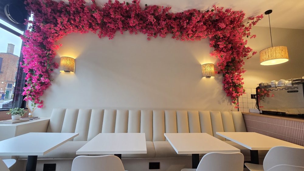 The seating area at Urbano Bakery & Café, cream banquette, marble tables and a pink bougainvillea arch