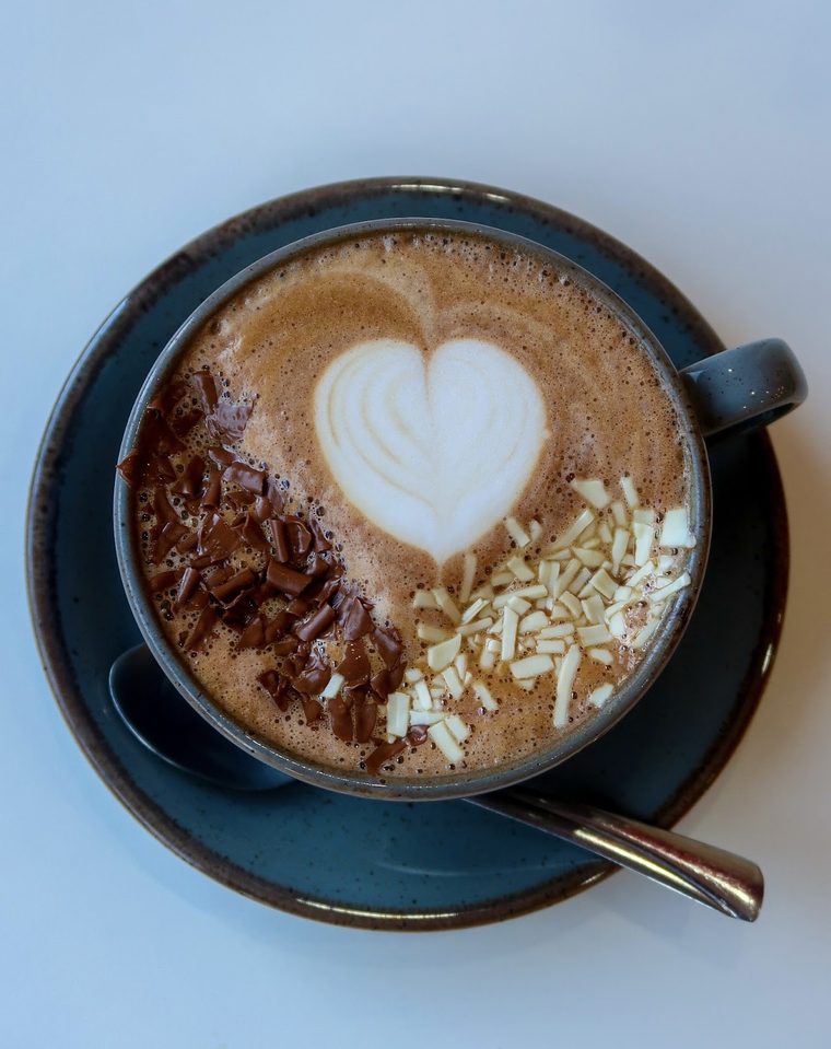 Cappuccino with heart latte art in a dark blue cup